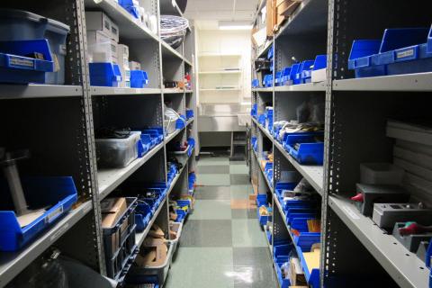 An aisle in the stockroom, with supplies in blue containers